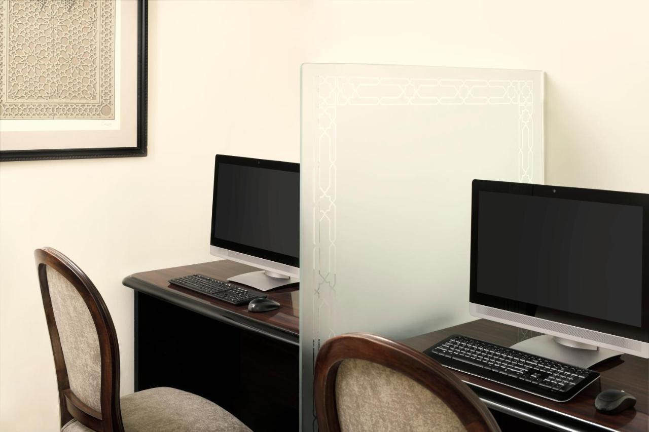 Готель Intercontinental Dar Al Iman Madinah By Ihg Medina Екстер'єр фото The photo shows a workspace featuring two computers set up on a dark wooden desk. Each computer has a monitor and a keyboard. A frosted glass partition is placed between the two workstations, providing some privacy. In the background, there is a fram