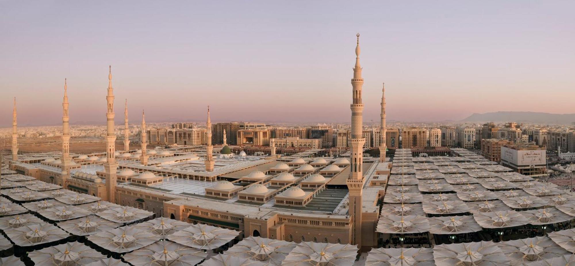 Готель Intercontinental Dar Al Iman Madinah By Ihg Medina Екстер'єр фото The photo shows an aerial view of the Al-Masjid an-Nabawi, or the Prophet's Mosque, located in Medina, Saudi Arabia. The mosque features distinct minarets, large white domes, and expansive open areas with large umbrellas that provide shade for visito