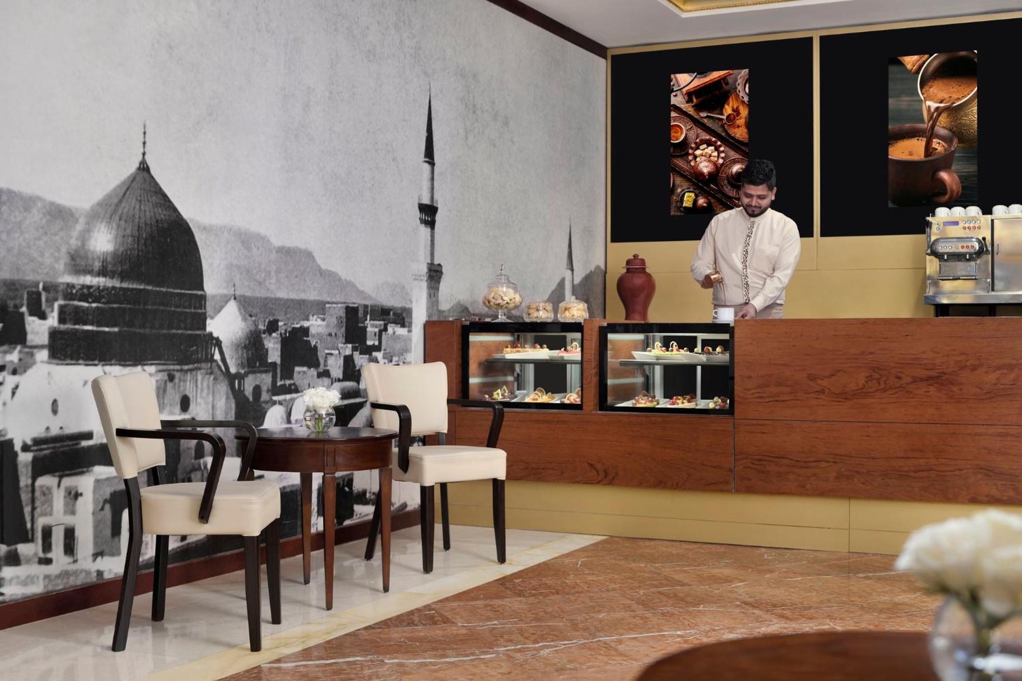 Готель Intercontinental Dar Al Iman Madinah By Ihg Medina Екстер'єр фото The photo shows a stylish interior of a café or pastry shop. In the background, there is a large black-and-white mural depicting a cityscape, featuring a prominent dome and minaret, suggesting an architectural style that could be from a Middle Easter