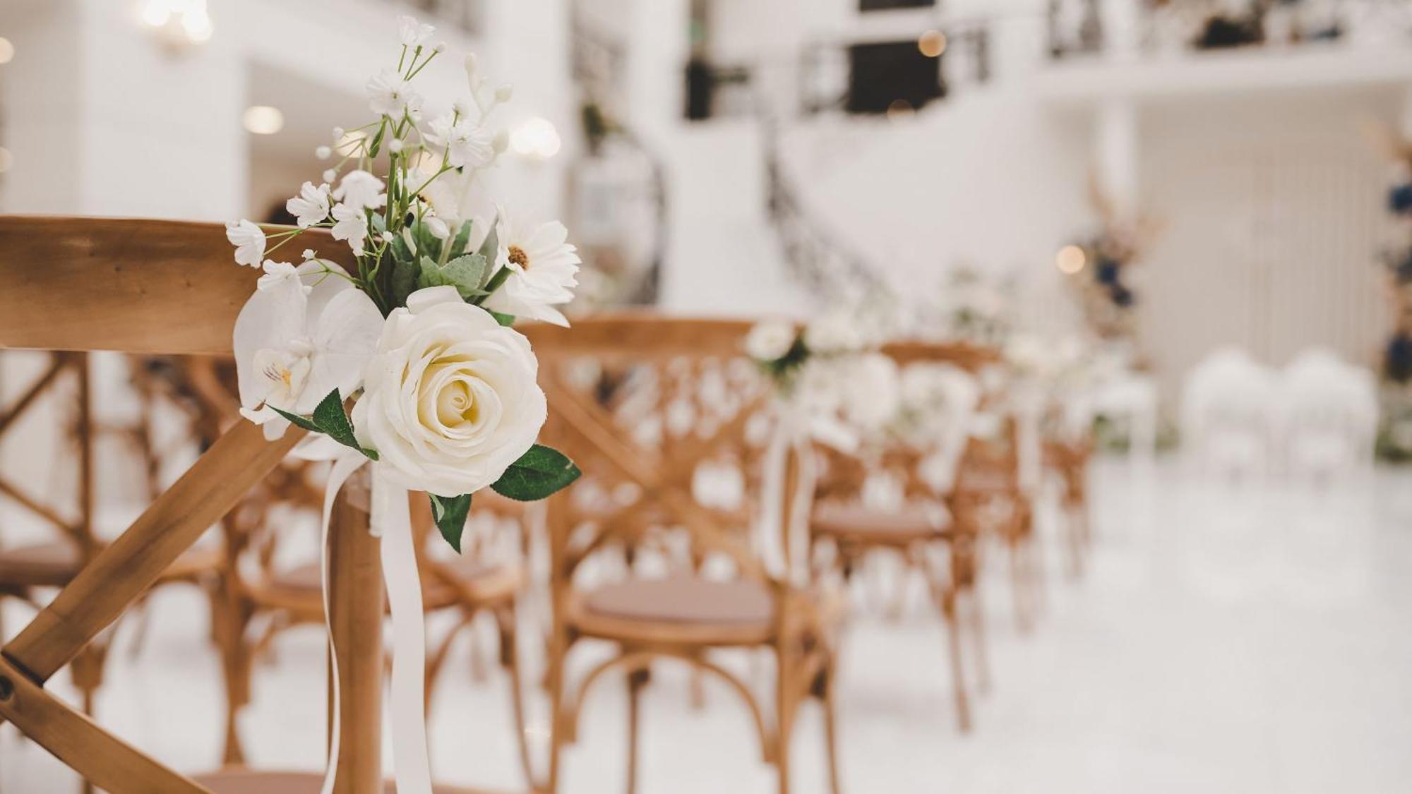 Готель Intercontinental Dar Al Iman Madinah By Ihg Medina Екстер'єр фото The photo showcases a beautifully arranged event space, likely set up for a wedding or special occasion. In the foreground, wooden chairs are neatly lined up, some adorned with decorative floral arrangements. The flowers include white roses and small