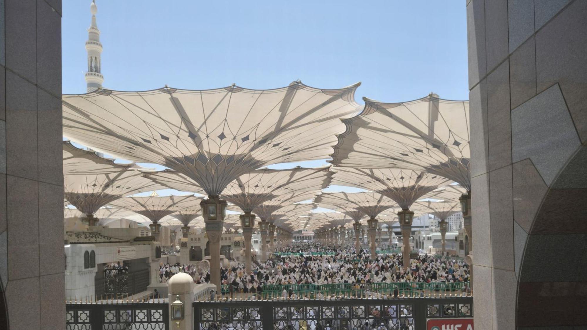 Готель Intercontinental Dar Al Iman Madinah By Ihg Medina Екстер'єр фото The photo shows a large open area covered by expansive canopies, likely designed to provide shade for the people below. Underneath the canopies, there are many individuals gathered, possibly participating in a religious event or gathering. In the bac