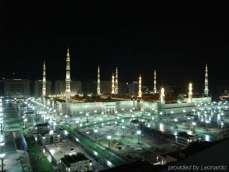 Готель Intercontinental Dar Al Iman Madinah By Ihg Medina Зручності фото The image shows the illuminated landscape of a mosque complex at night. It features several tall minarets, which are typically part of Islamic architecture, adorned with lights. The mosque's central building is also brightly lit, surrounded by an ope
